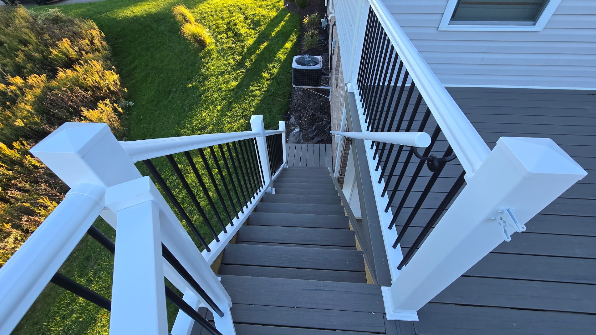 Deck stair railing with white vinyl posts and black aluminum balusters in Moon Township