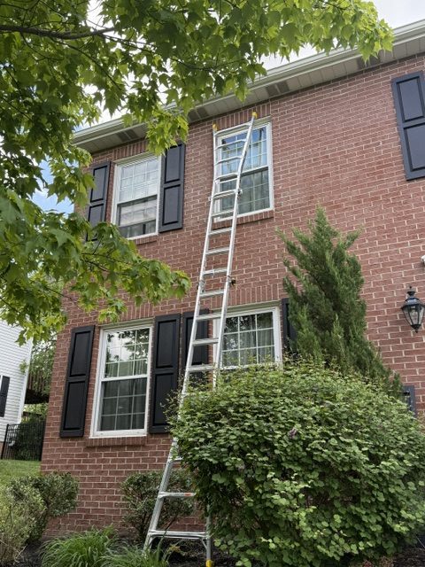 Ladder set for exterior shutter repair on a brick two-story home in Moon Township
